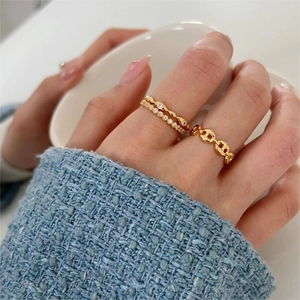 Close-up of three stacked gold rings with cubic zirconia on model holding a cup