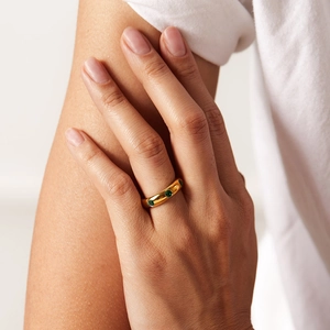 Detailed view of a gold-plated ring with inlaid green zircon stones on a model hand