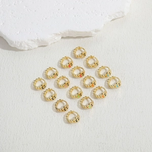 Macro view of gold-plated twisted hoops with colorful enamel smiley faces in various colors