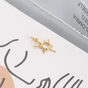Macro detail of sunburst charm in 18K gold plated copper with central ring design
