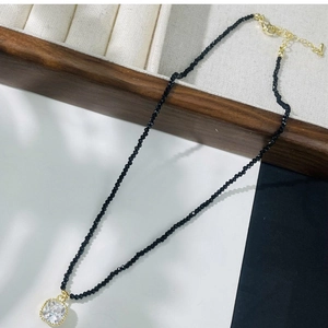 Gros plan d'un collier en perles de cristal noir avec un pendentif en cristal carré.