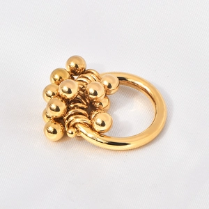 Detail of 18K gold plated ring with cluster of polished metallic spheres on white fabric