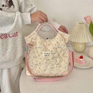 Close-up of quilted cream tote bag featuring cute cartoon animal prints and pink woven handles