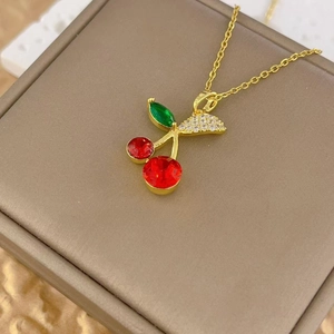 Detailed close-up of cherry pendant necklace with red crystals and gold-plated chain
