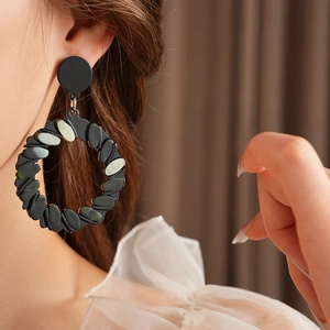 Close-up of stylish green resin twisted geometric earrings worn by a female model