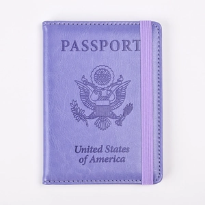 Detalle de funda de pasaporte en cuero púrpura con banda elástica y logo de Estados Unidos