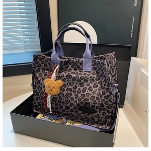 Close-up of leopard print canvas tote bag with purple straps and cute bear pendant