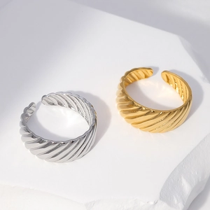 18k gold and silver plated twisted croissant open rings on a white textured stone surface
