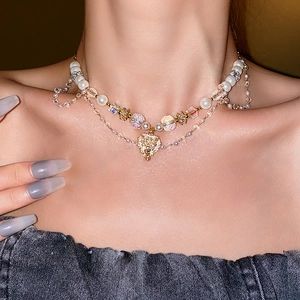 Detail view of multi-layered pearl and crystal heart pendant necklace on a model