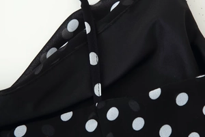 Detailed macro view of black polka dot fabric with delicate spaghetti straps