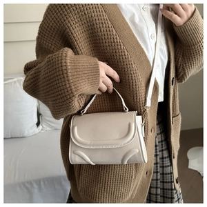 Detailed view of creamy matte leather handbag worn by model with matching shoulder strap