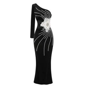 Détails d'une robe noire à une épaule avec fleur blanche et ornements en perles et strass