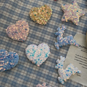 Macro shot of sequined heart and star ornaments on blue checkered fabric background