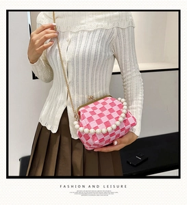 Detail of pink and white checkered clutch with pearl handle and golden chain strap