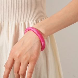 Detail shot of a rose pink marble resin bangle worn on wrist with elegant minimalist style
