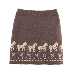 Detail of brown knit skirt featuring jacquard pony and blue bow patterns in thick fabric