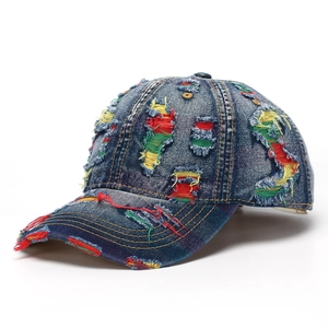Close-up of distressed denim baseball cap featuring colorful ripped holes and frayed edges