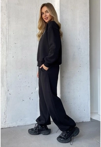 Full-body profile of woman wearing a black heart-print sweatshirt and drawstring sweatpants