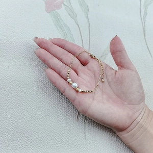 Detail of elegant gold bracelet with three white pearls and lobster clasp on woman's wrist