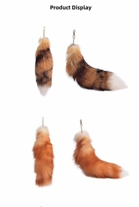 Detail of oversized faux fur fox tail keychains in orange and natural brown tones