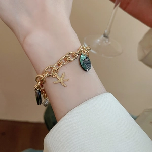 Close-up of golden link bracelet with starfish charm and vintage oval pendants