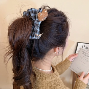 Detailed close-up of a large grey plaid bow hairclip with a cute brown plush bear charm