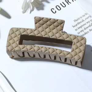 Detail of beige matte hair claw clip featuring a classic quilted texture for women