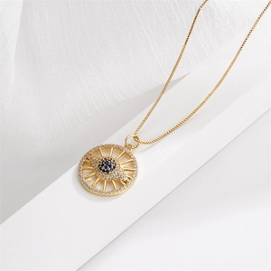 Macro detail of gold evil eye pendant with blue zircon stones on textured white fabric