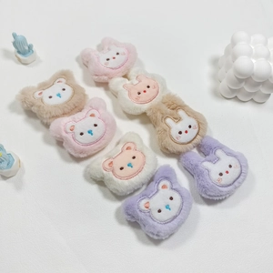 Cute plush bear and bunny hair accessories in various pastel colors on a white desk