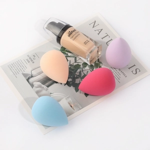 Set of 4 soft colorful makeup sponges with liquid foundation on a minimalist background
