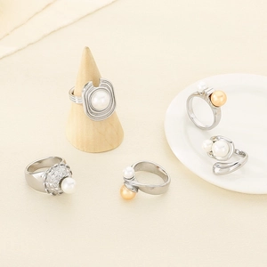 Macro detail of textured stainless steel rings with pearl inlays on a ceramic dish