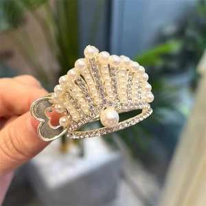 Macro shot of silver crown hair claw clip with pearls and rhinestones on blurred background