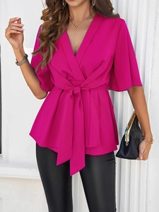 Détail de la blouse rose fuchsia à col en V avec ceinture et manches évasées élégantes