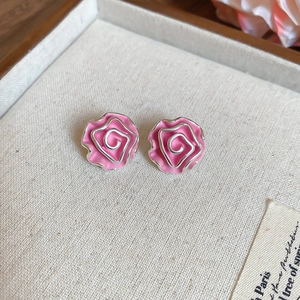 Close-up of pink rose earrings with silver outlines in a jewelry storage tray
