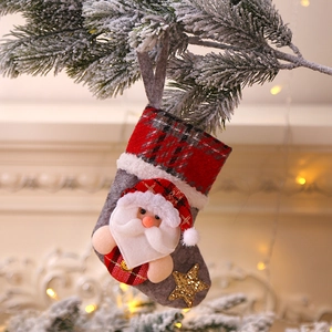 Detail of grey felt Christmas stocking with Santa doll hanging on snow-covered pine branch
