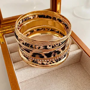 Golden multi-layer bangles with leopard print and rhinestones on a linen jewelry tray