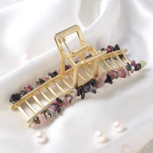 Golden metal hair claw clip with colorful natural quartz crystals on white silk