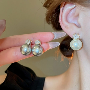 Détail de boucles d'oreilles élégantes avec zircon carré et grandes perles rondes
