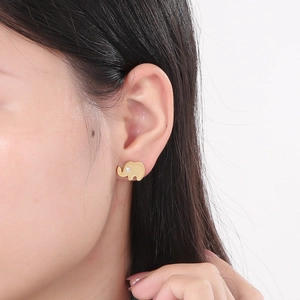 Detail of a golden elephant stud earring featuring a small white rhinestone on a model's ear