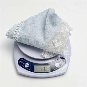 Light blue floral scarf with white lace trim weighing 20.3g on a precision digital scale