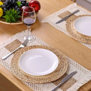Detail of round straw placemat and rectangular woven cotton linen table mat on wood