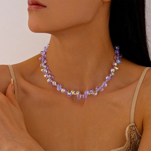 Detailaufnahme eines lila facettierten Kristall-Chokers am Hals mit weichem Licht