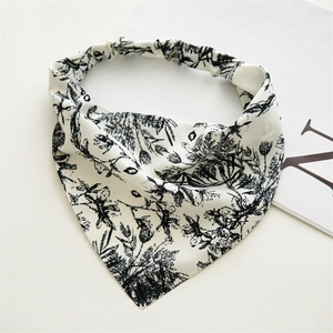 Dettaglio di un foulard a triangolo bianco con stampa floreale nera ed elastico