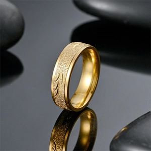 Detailed macro view of gold titanium ring with leaf engraving on black mirror surface