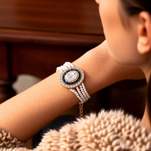 Detail of multilayer pearl bracelet featuring a blue enamel oval clasp with clear gemstone