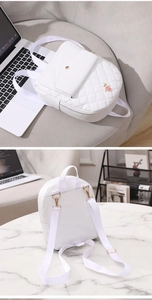 Detail showing the white quilted backpack with a metal rose buckle and dual viewing angles