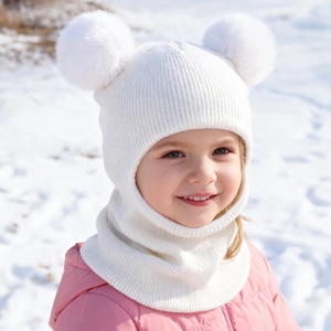 Detail of white knit baby hood with soft ribbing and two large fluffy pom-poms