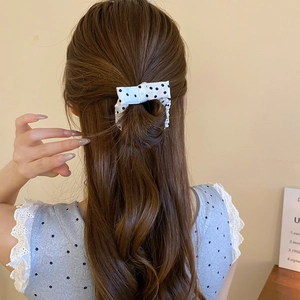 Detailed back view of a woman wearing a cream polka dot bow scrunchie on a ponytail