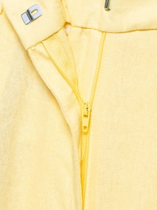 Detailed close-up of zipper and metal hook closure on lemon yellow cotton linen trousers