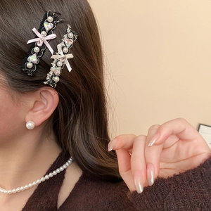 Detail of lace bow hair clip with pink silk, pearls, and a heart gemstone on model
